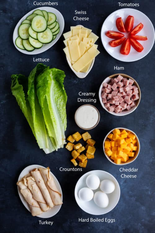 Overhead view of ingredients to make a Chef salad on a dark blue surface