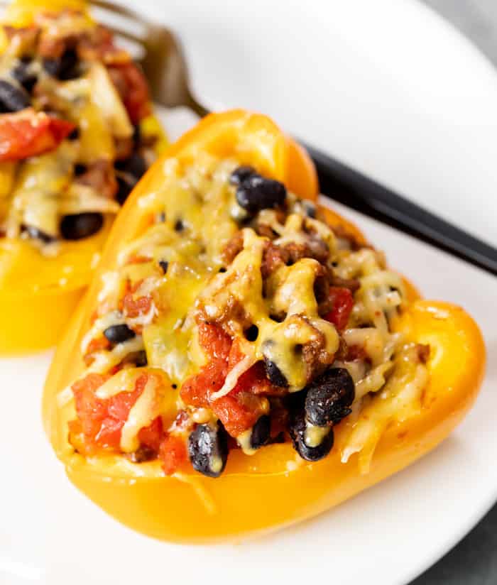 A taco stuffed pepper pepper on a white plate with a fork in the background.