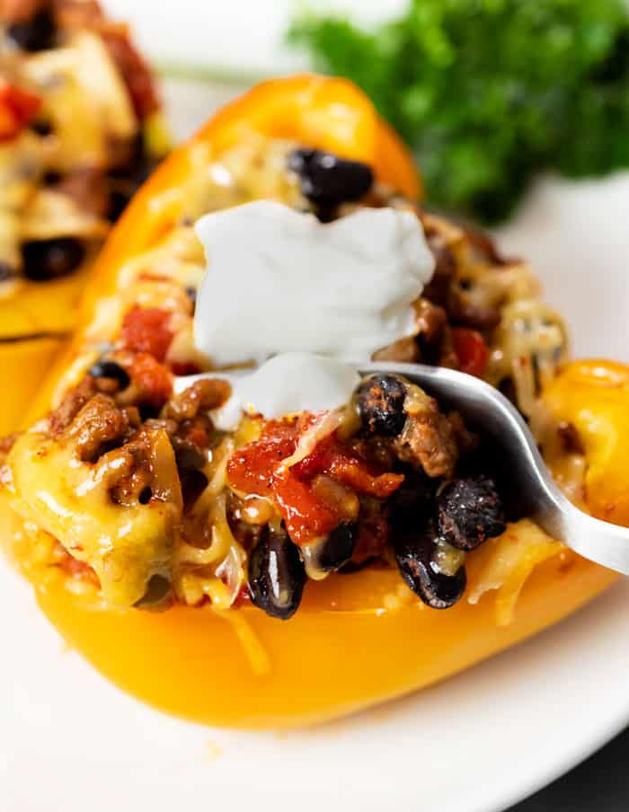 Half of a yellow bell pepper stuffed with taco filling and topped with melted cheese and sour cream.