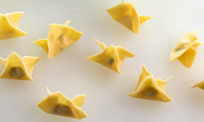 overhead shot of uncooked, folded wonton wrappers for crab rangoon