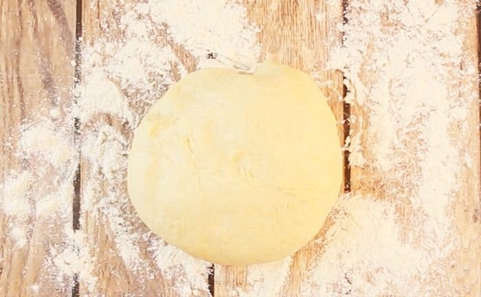 Round ball of roll dough on floured wooden surface