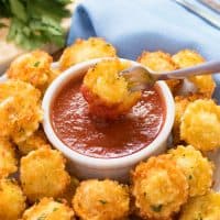 Parmesan Crusted Tortellini Bites with a fork dipping one into Marinara sauce.
