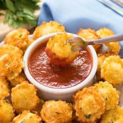 Parmesan Crusted Tortellini Bites with a fork dipping one into Marinara sauce.