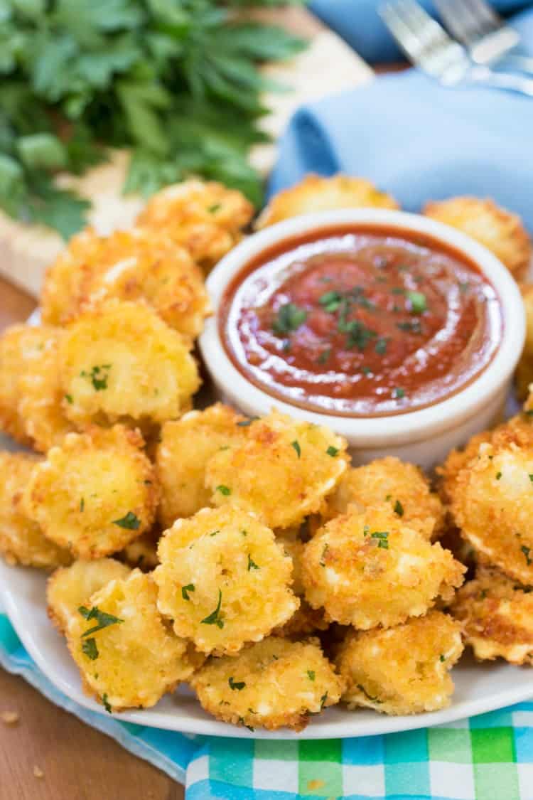 a plate of breaded, fried tortellini with marinara sauce in background.