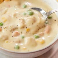 A close up view of a spoon in a creamy bowl of Chicken Pot Pie Soup.