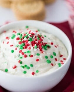 A white bowl of Christmas cookie dip with red and green sprinkles on top.