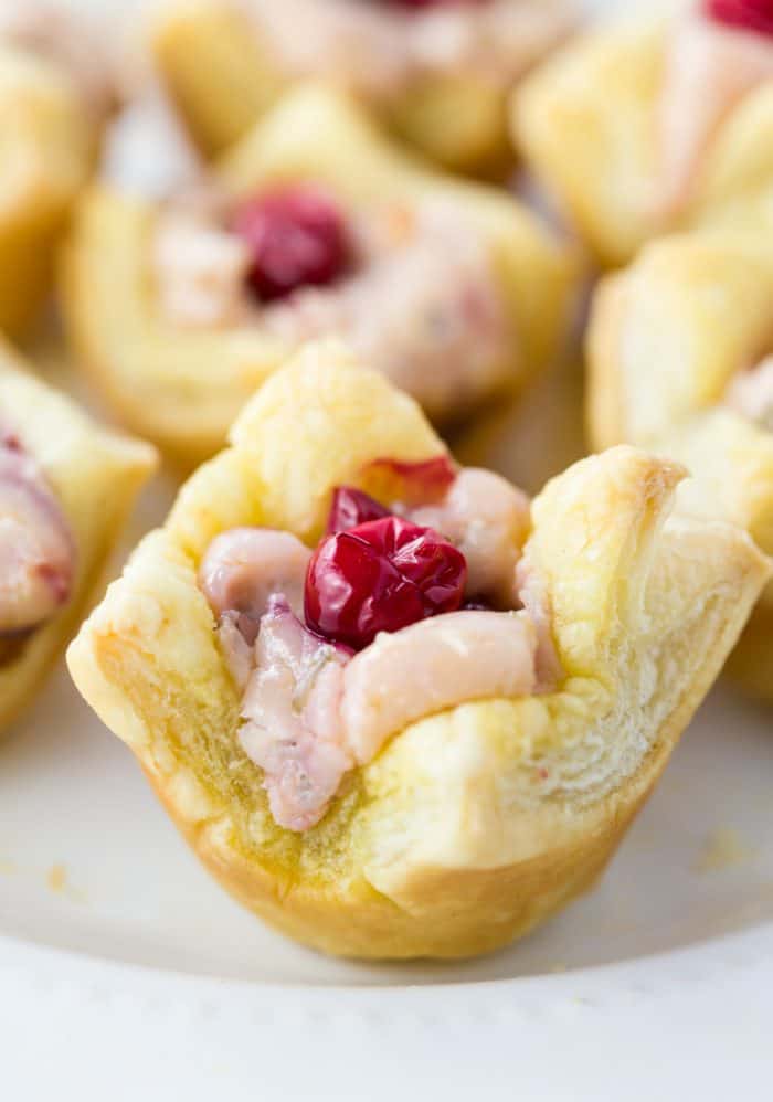 Cream Cheese Cranberry Tartlets topped with fresh cranberries on a white surface.