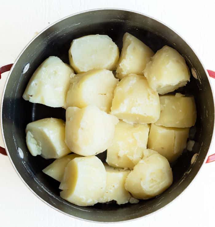 A large pot filled with cooked and boiled russet potatoes.