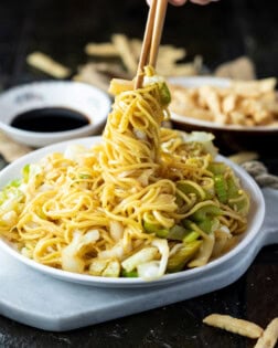 A white plate with Panda Express Chow Mein being twisted up with chopsticks.