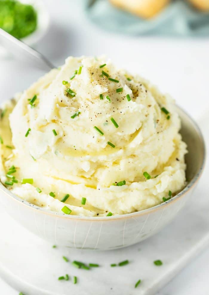 Mashed Potatoes in a small bowl topped with chopped chives and pepper.