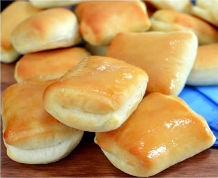 Three texas roadhouse rolls stacked on top of each other, shining with melted butter on top