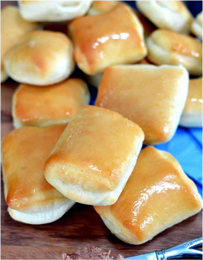 Several Texas Roadhouse Rolls Stacked up on top of each other, glistening with butter on top