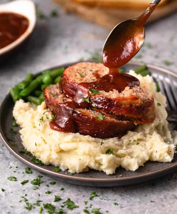 Meatloaf over mashed potatoes with a homemade ketchup sauce drizzled on top