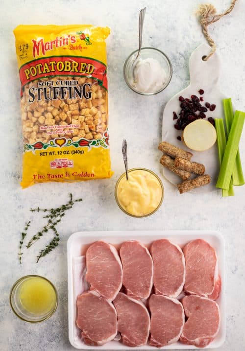 Ovehead shot of bag of stuffing, Tray of uncooked Pork chops, and other stuffing ingredients