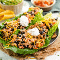 A plate with turkey taco lettuce wraps topped with sour cream.