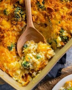 broccoli chicken rice casserole in a casserole dish with a wooden spoon in it.