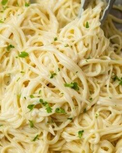 Garlic Parmesan Pasta in a skillet with kitchen tongs topped with parsley.