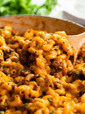A skillet with a wooden spoon scooping up Cheeseburger Casserole