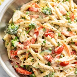 Pasta Primavera in a creamy sauce with vegetables in a stainless steel skillet.