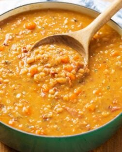 A soup pot filled with Ham and Bean soup with a wooden spoon.