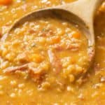 A wooden spoon full of thick and hearty Ham and Bean Soup.