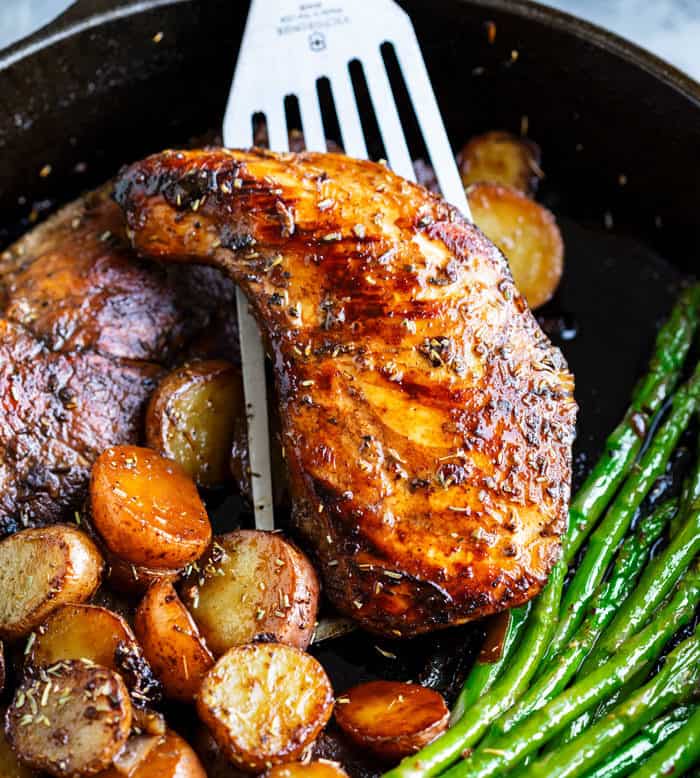 Seared Balsamic Chicken in a skillet with potatoes and asparagus.