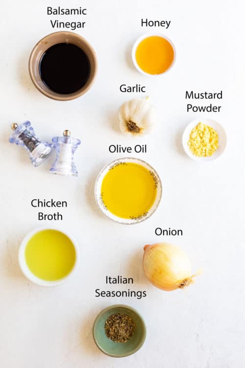 Overhead view of ingredients needed to make balsamic marinade on a white surface.