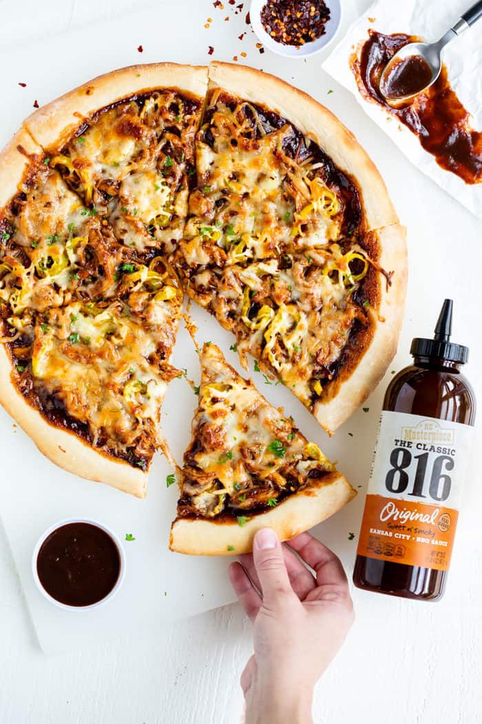BBQ Chicken Pizza next to a bottle of BBQ Sauce on a white surface.
