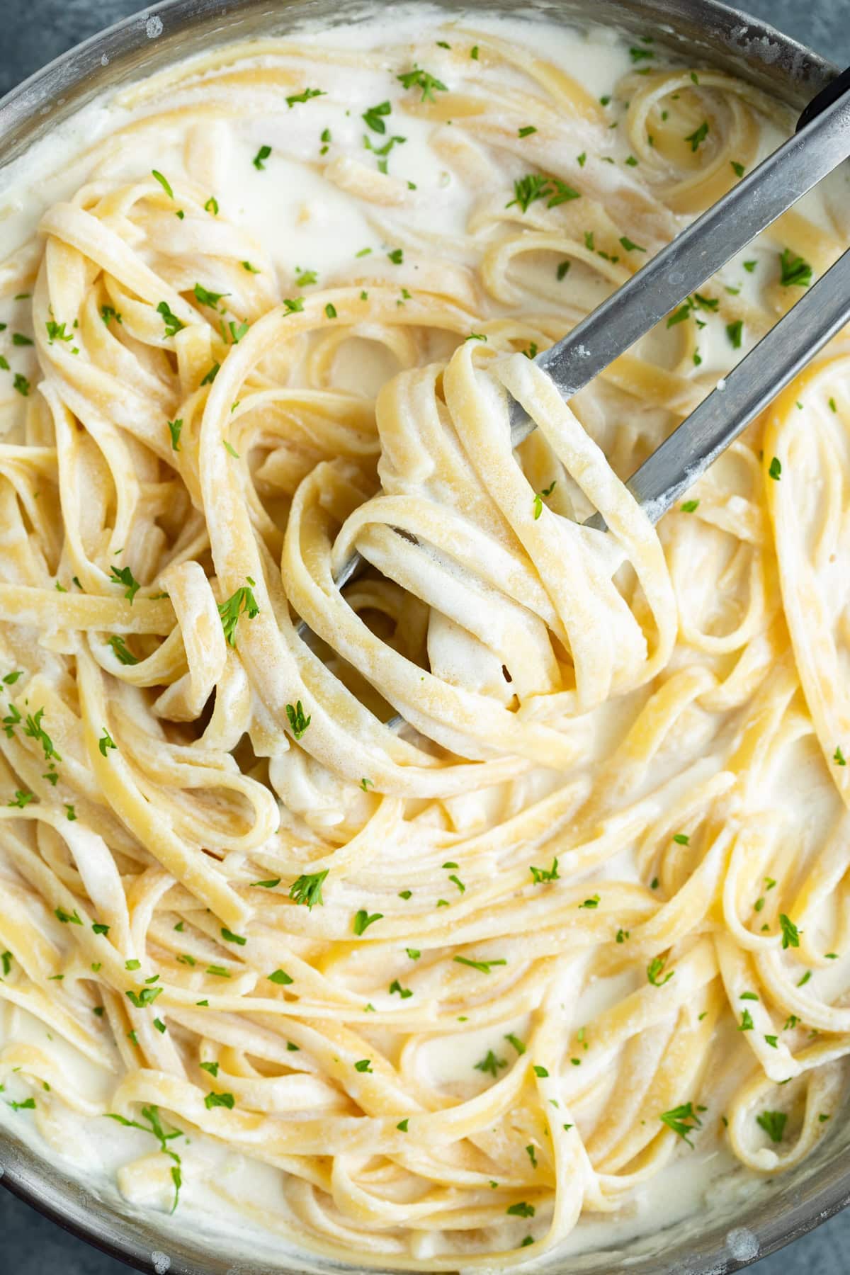 Fettuccine tossed in homemade Olive Garden Alfredo Sauce with fresh parsley on top.