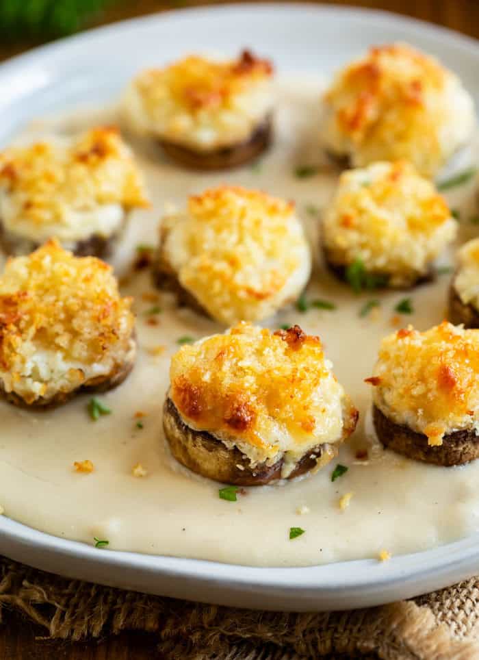 A plate topped with white cheddar cheese sauce and Parmesan Panko stuffed mushrooms.