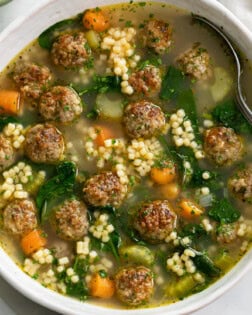 Italian Wedding Soup in a white bowl with meatballs, spinach, and acini de pepe.