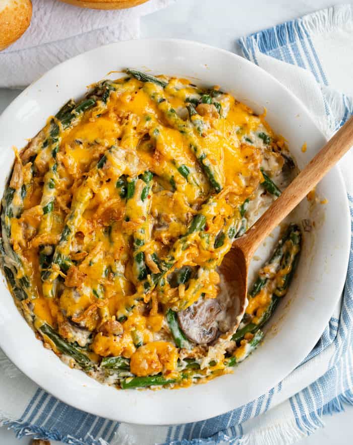 A white bowl filled with green bean casserole topped with melted cheese.