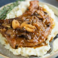 French Onion Smothered Pork Chops on a pile of mashed potatoes.