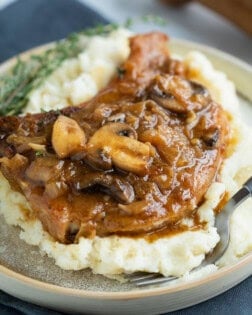 French Onion Smothered Pork Chops on a pile of mashed potatoes.