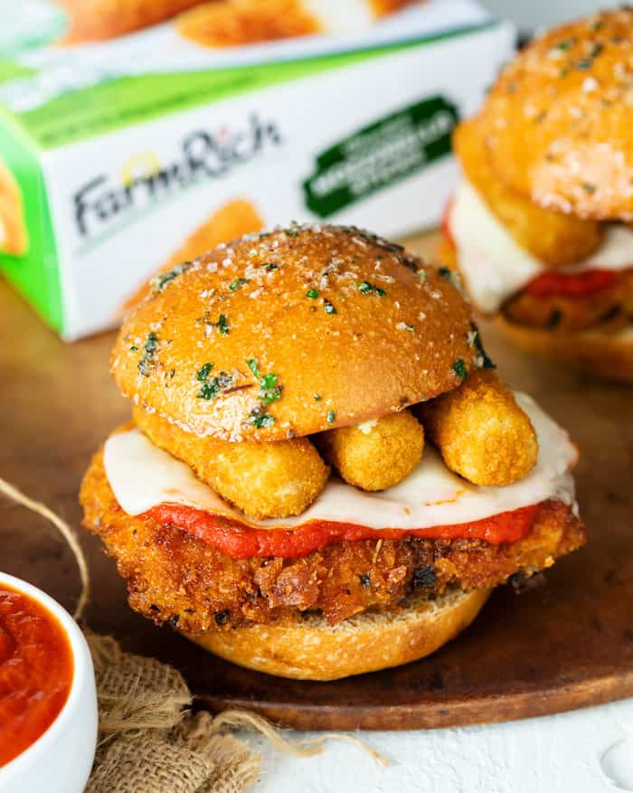 A Chicken Parmesan Slider topped with mozzarella sticks with a Farm Rich box in the background.