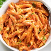 A white bowl of Penne Alla Vodka with parsley on top.