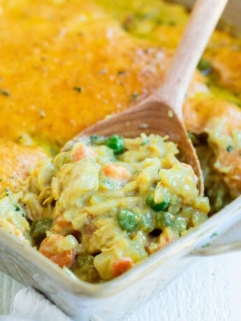 Bisquick Chicken pot pie in a casserole dish with a wooden spoon scooping it up.