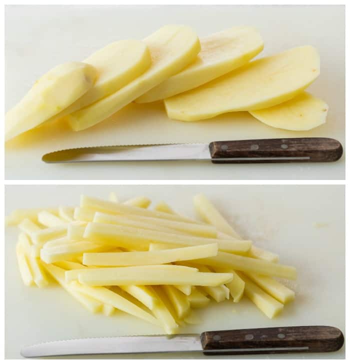 A peeled russet potato being cut into shoe strings on a white cutting board with a knife to make french fries.
