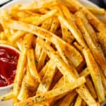 Seasoned french fries on a white plate.