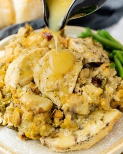 A plate of crock pot chicken and stuffing with gravy being poured on top.