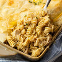 A scoop of French Onion Chicken Noodle Casserole being lifted from a casserole dish.