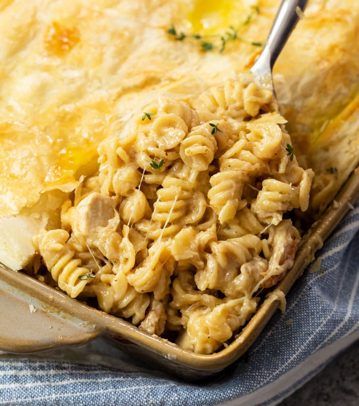 A scoop of French Onion Chicken Noodle Casserole being lifted from a casserole dish.