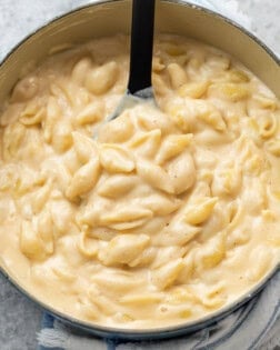 A pot filled with pasta shells in a creamy white cheddar cheese sauce for Panera mac and cheese recipe.