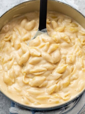 A pot filled with pasta shells in a creamy white cheddar cheese sauce for Panera mac and cheese recipe.