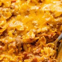 A casserole dish filled with sloppy joe casserole with a big spoon scooping it up.