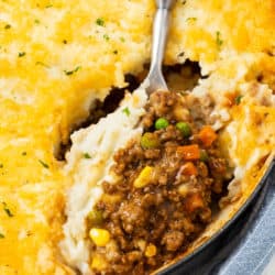 A large spoon scooping Shepherds Pie from a casserole dish.