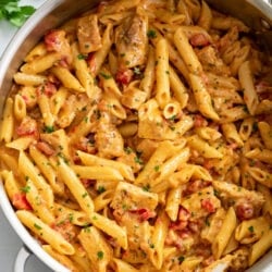 Cajun Chicken Pasta in a skillet with penne pasta, cream sauce, and tomatoes.