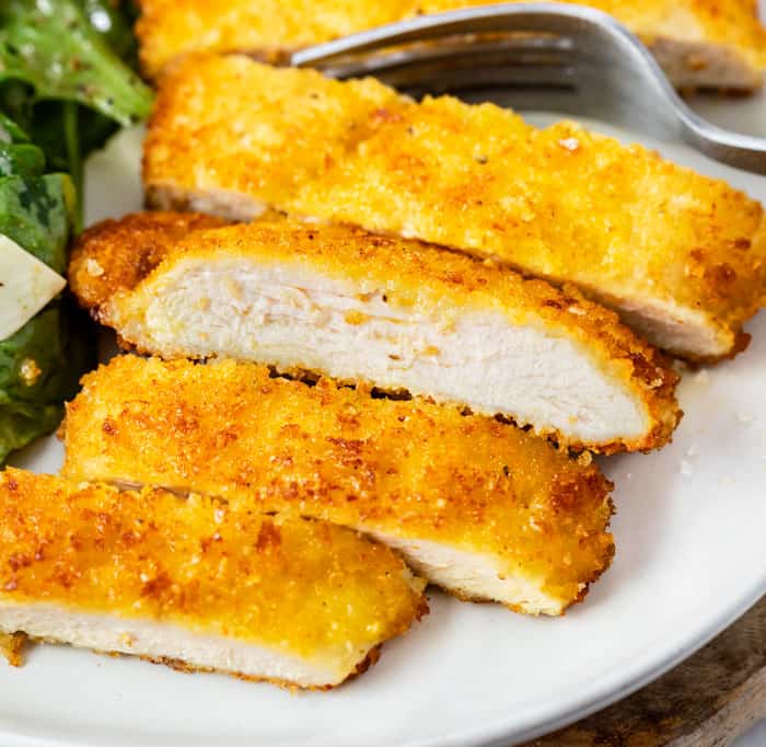 Slices of crispy breaded chicken Milanese on a plate.