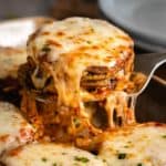 Eggplant Parmesan being pulled up from a casserole dish with hot mozzarella cheese on top.
