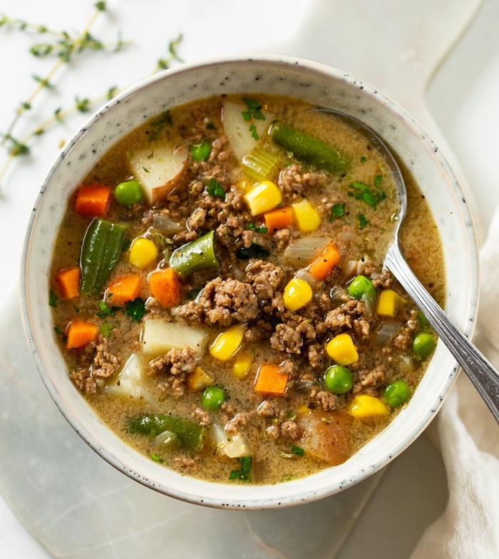 A white bowl of Hamburger Soup with vegetables and ground beef.